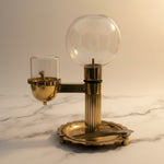 Brass akhand diya with glass globe oil reservoir on white marble - Divine Sansar
