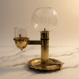 Brass akhand diya with glass globe oil reservoir on white marble - Divine Sansar