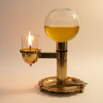 Lit brass akhand diya with oil-filled glass globe reservoir - Divine Sansar