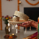 Mehndi hands holding the Classic Elegance orange and gold Karwa Chauth thali with zari lace chhalni - Divine Sansar