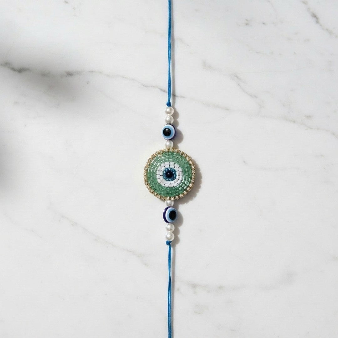 Green beaded evil eye nazar rakhi on marble - Divine Sansar