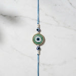 Green beaded evil eye nazar rakhi on marble - Divine Sansar