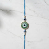 Green beaded evil eye nazar rakhi on marble - Divine Sansar