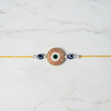 Peach beaded evil eye nazar rakhi on marble - Divine Sansar