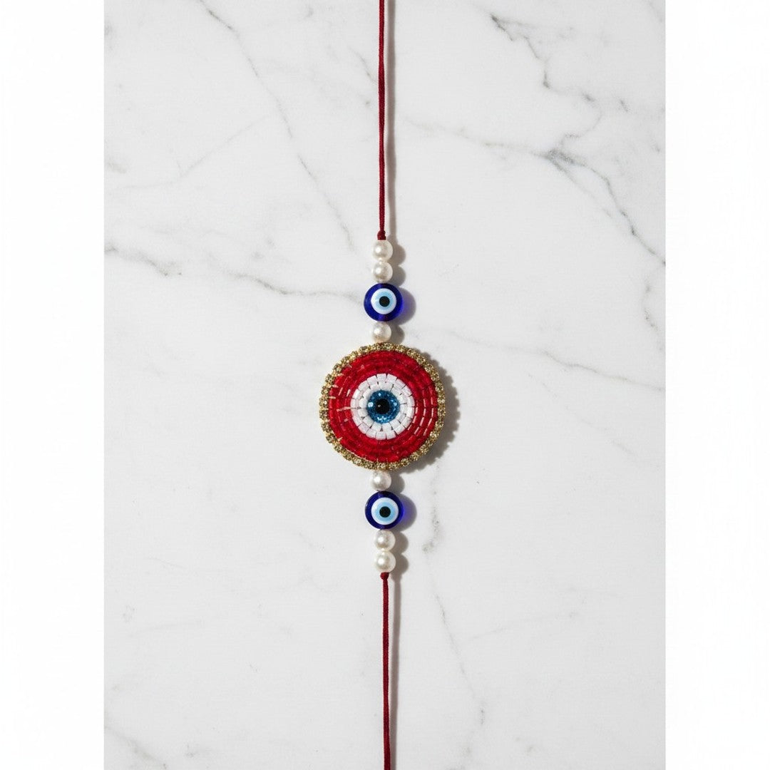 Red beaded evil eye nazar rakhi on marble - Divine Sansar