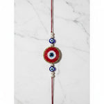 Red beaded evil eye nazar rakhi on marble - Divine Sansar