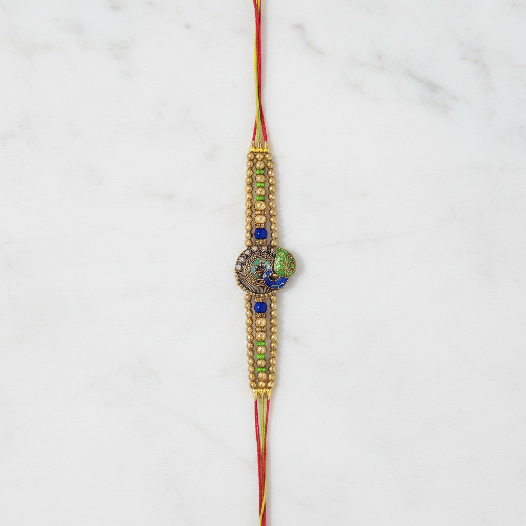 Mayura Tejas Gold Peacock Meenakari Rakhi on marble - Divine Sansar UAE
