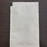 Divine Sansar-White paper pouch on a wooden surface