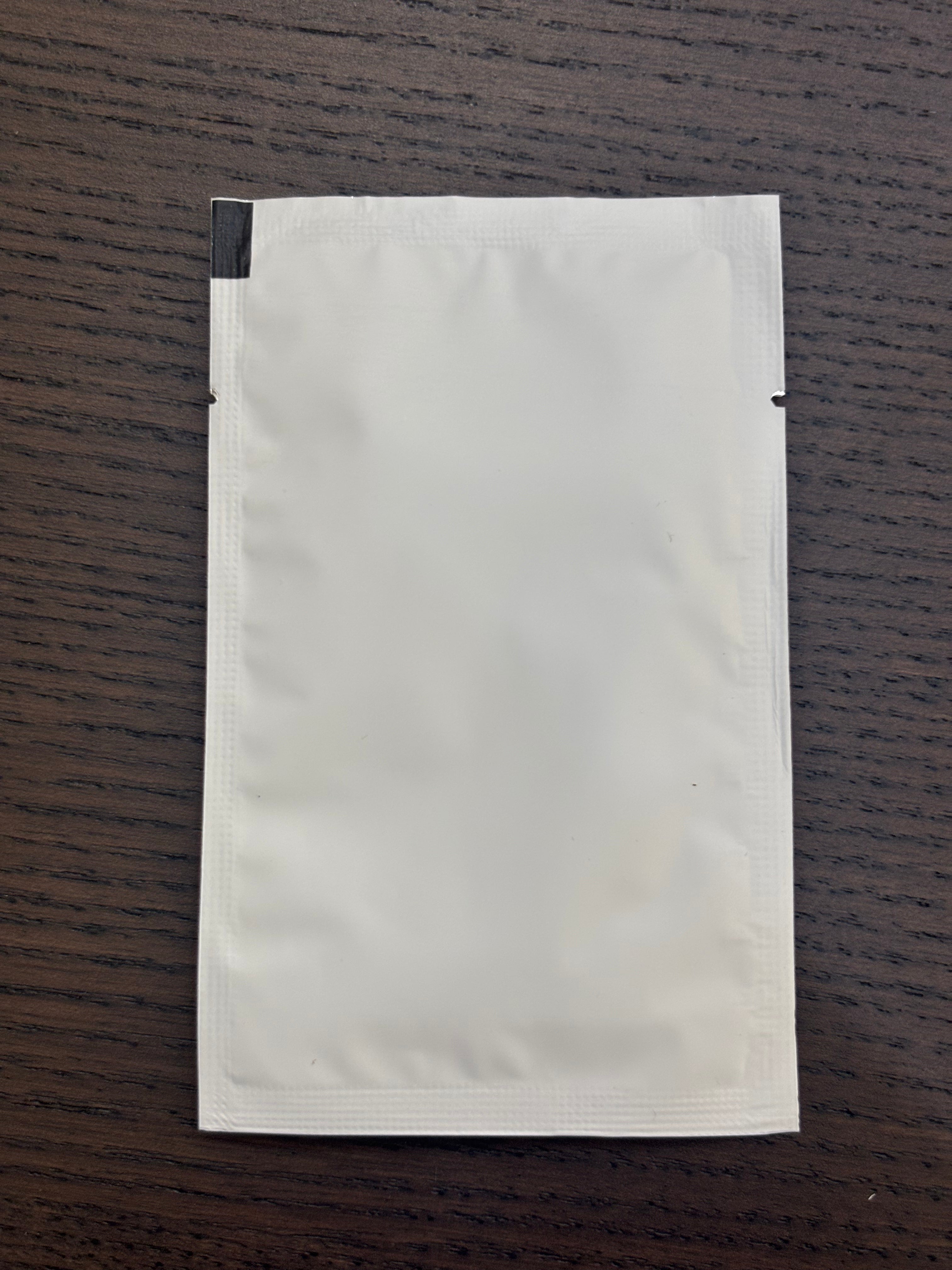 Divine Sansar-White paper pouch on a wooden surface