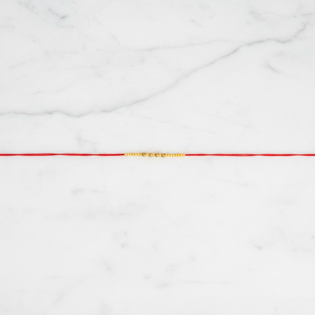 Saral Sutra Simple Beaded Rakhi on marble - Divine Sansar UAE