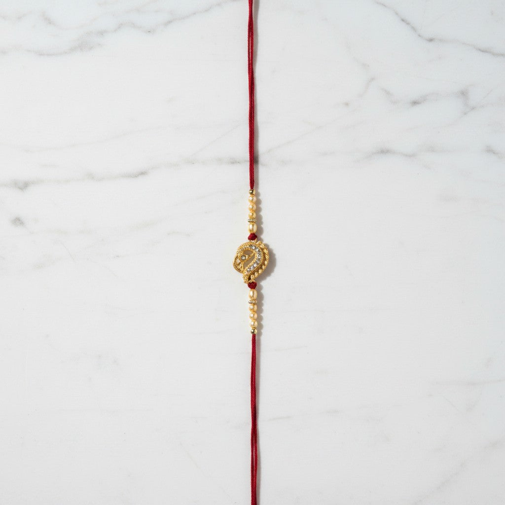 Swarna Mor Gold Peacock Rakhi on marble - Divine Sansar UAE